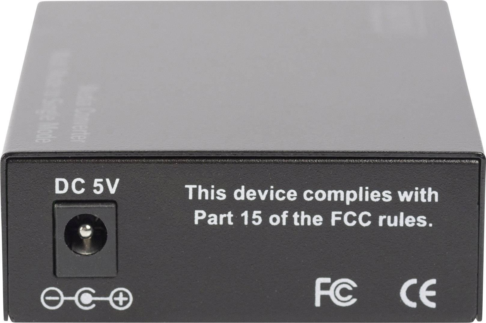 Zwarte elektronische doos met voedingsaansluiting links, tekst erop: 'Dit apparaat voldoet aan Deel 15 van de FCC-voorschriften', FCC- en CE-logo's.