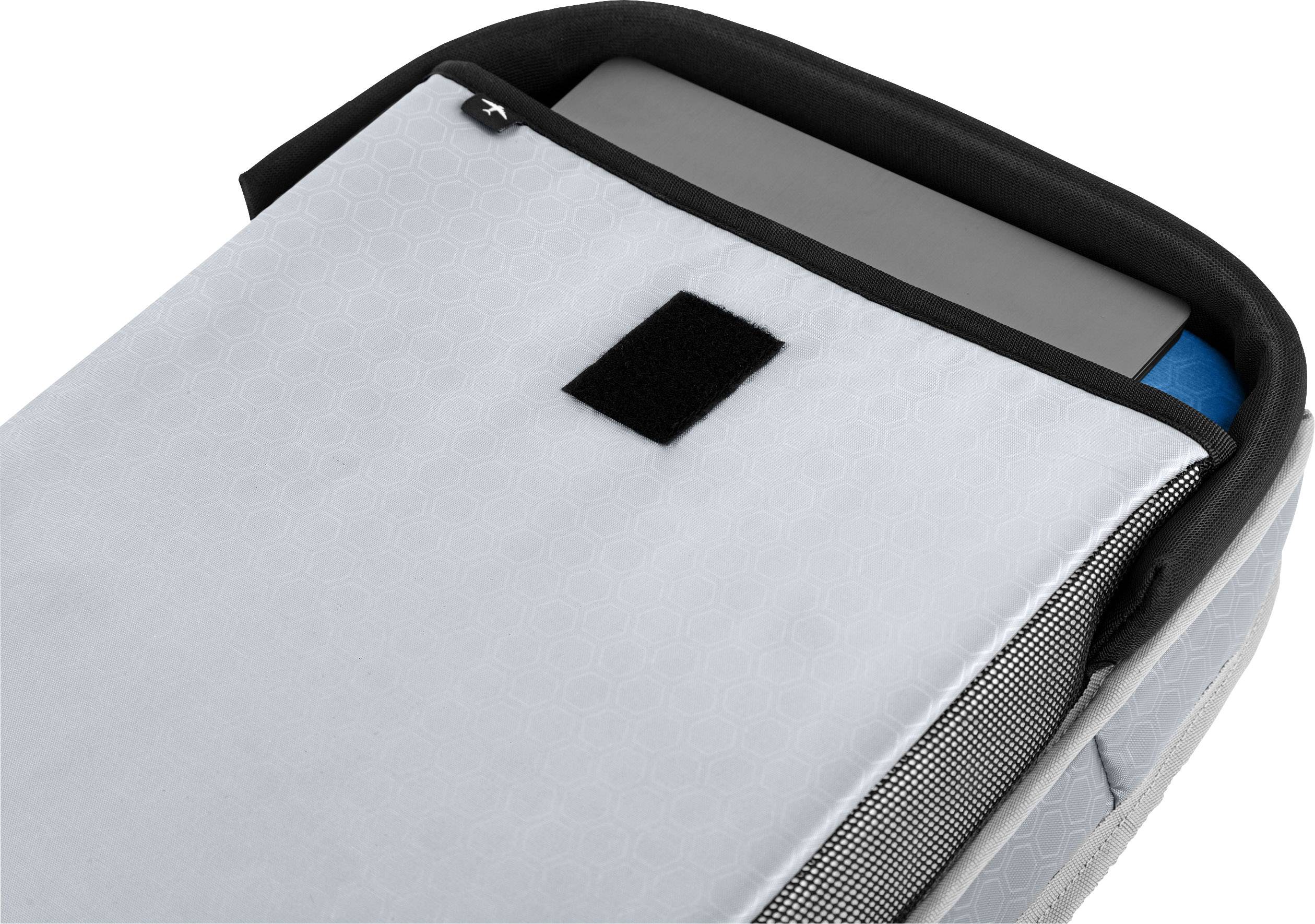 Een grijze laptoptas, licht geopend, onthult een gedeeltelijk zichtbare laptop en een blauw notitieboek.