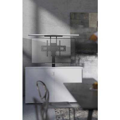 Een moderne ruimte met een witte kast, daarbovenop een steun voor een tv-apparaat, zonder beeldscherm gemonteerd. Schaduwspelen op de muur.