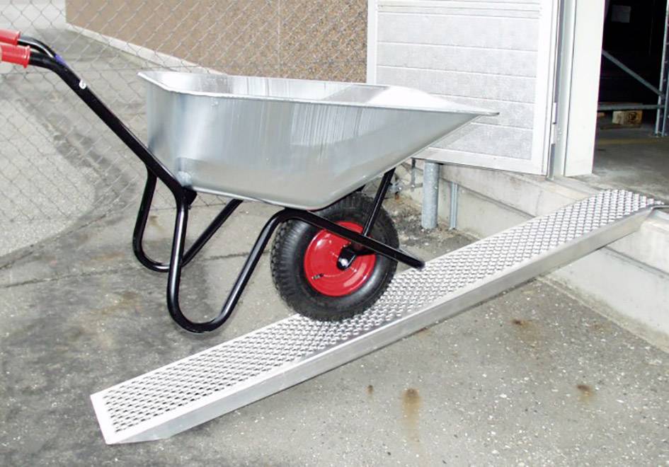 Kruiwagen met een rood wiel op een metalen oprit, klaar om te worden gelost in een gebouw.