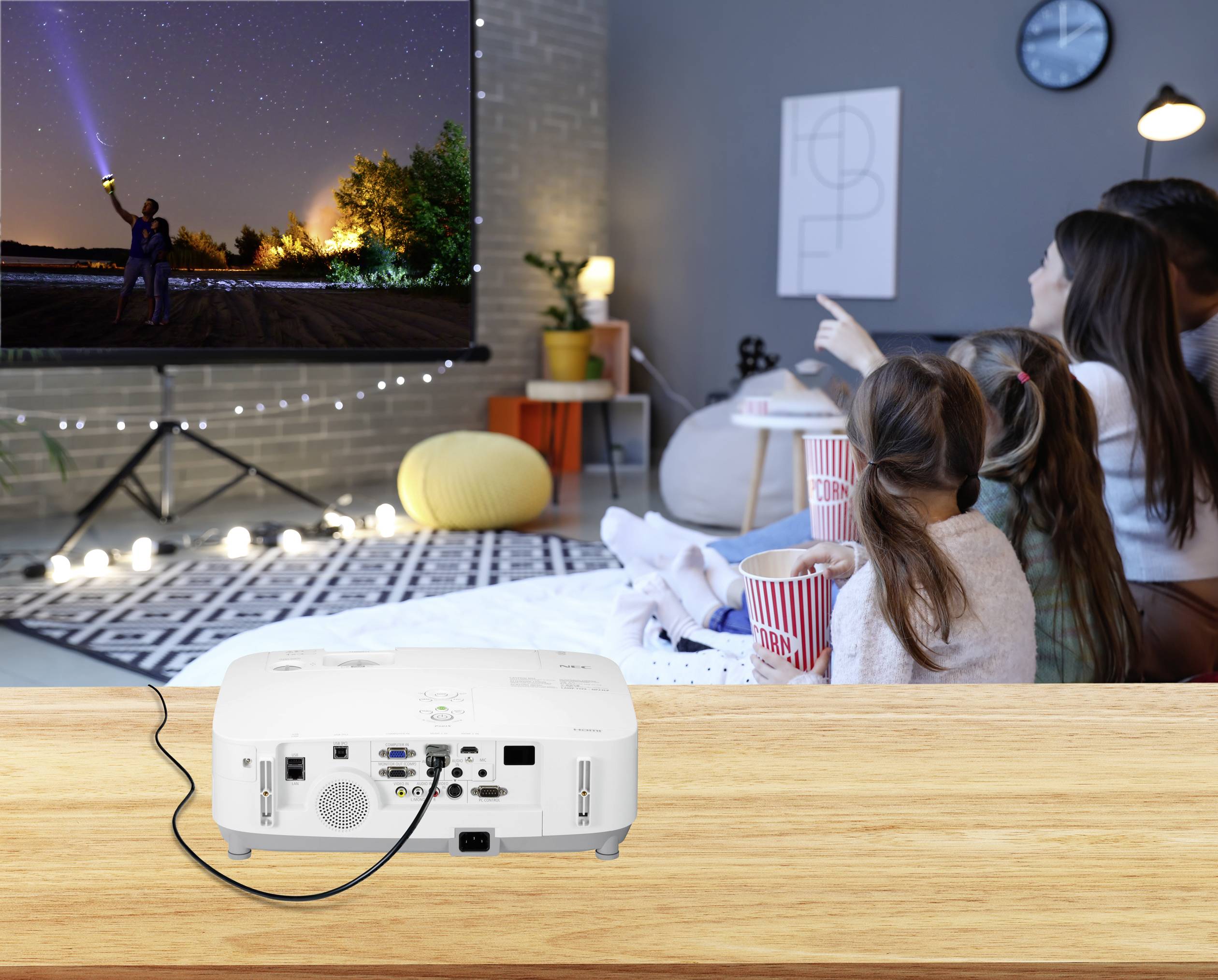 Familie kijkt naar een groot geprojecteerd beeld in de woonkamer. De ruimte is gezellig verlicht, met popcornschalen op de bank.