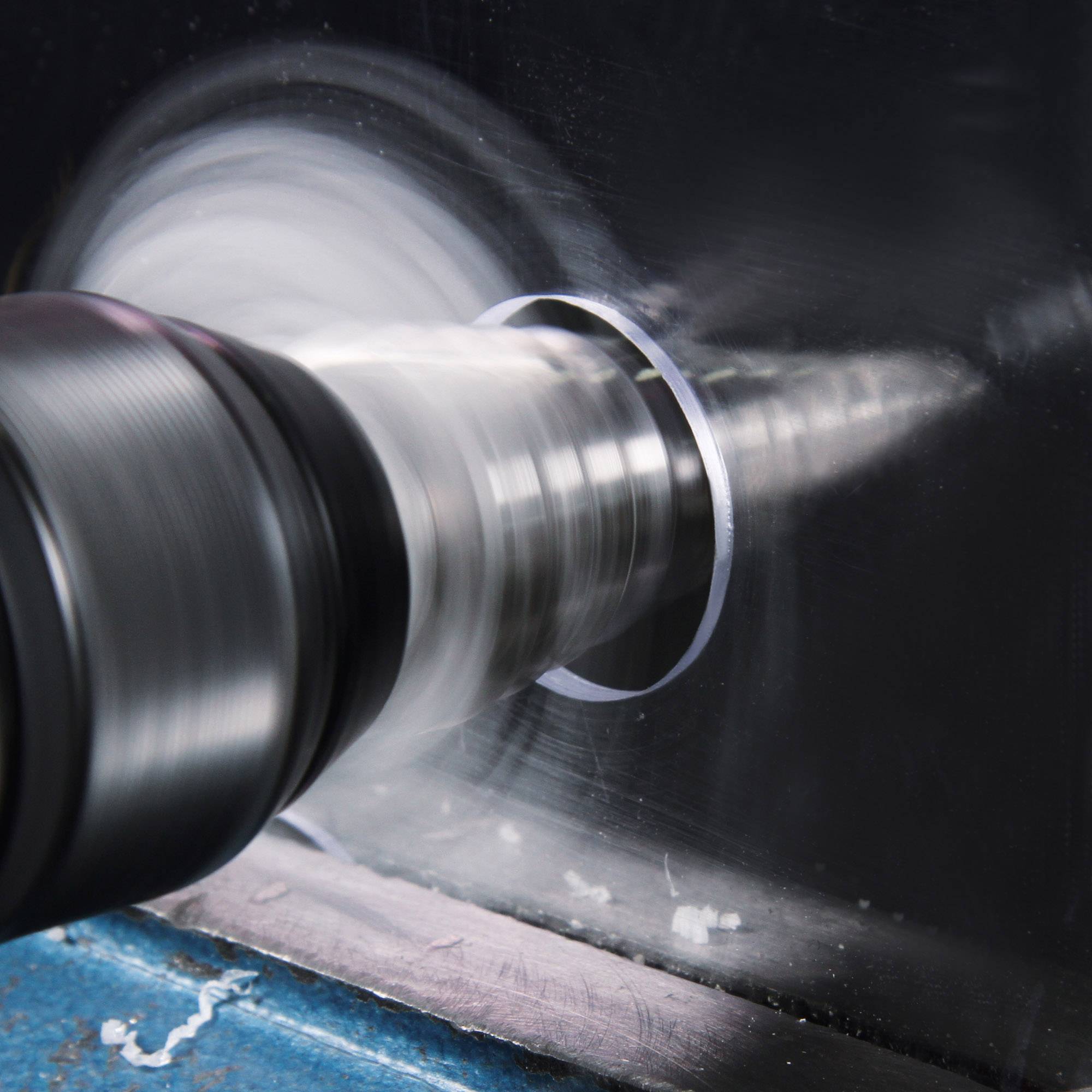 Een draaiende metalen boormachine boort door een zilveren metalen plaat en creëert een cirkelvormige doorsnede.