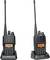 Twee zwarte portofoons met antennes en verlichte displays, die op laadstations staan.