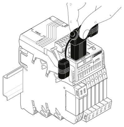 Een hand trekt een borgpal omhoog aan een elektrisch schakeltoestel om een component te verwijderen of te plaatsen.