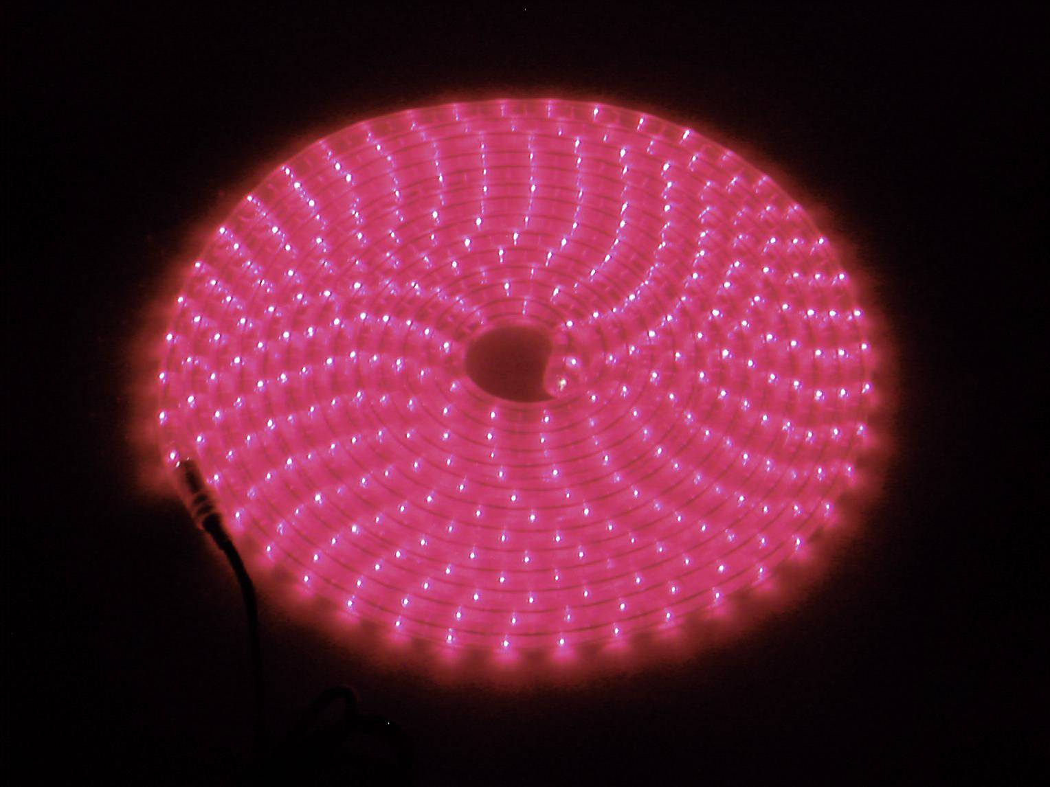 Een rood oplichtende LED-lichtslinger in spiraalvorm op een donkere achtergrond, die gelijkmatig licht uitstraalt.