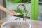 Een persoon vervangt de perlator van een waterkraan in een moderne keuken om water te besparen.