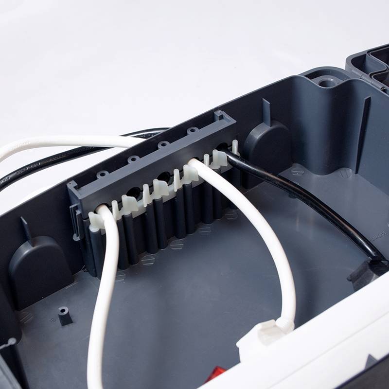 Een geopende elektrische behuizing met meerdere aangesloten kabels, waaronder zwarte en witte kabels.