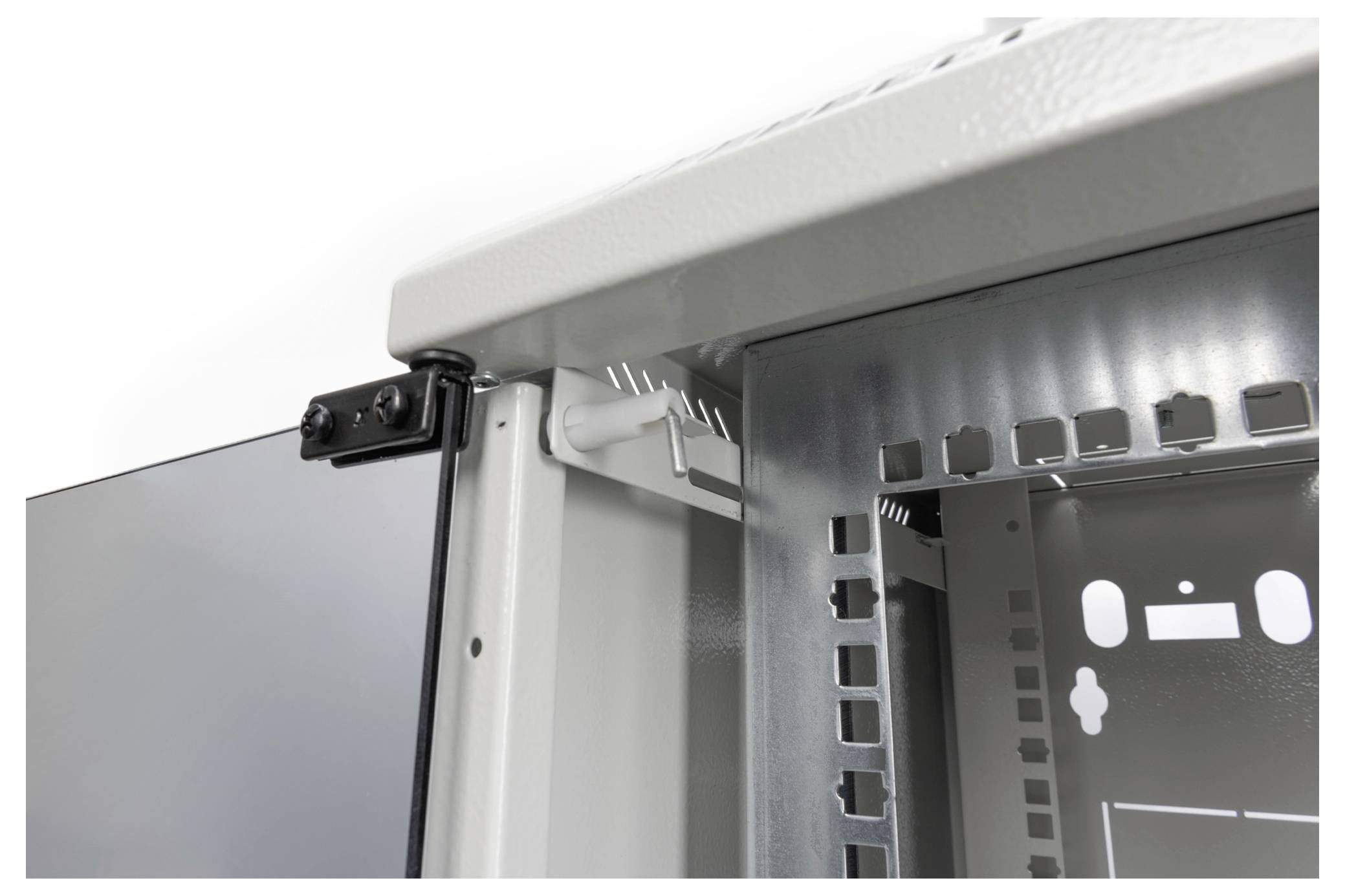 Close-up van een witte metalen kast met een glaselement. Scharnieren en rechthoekige openingen zijn zichtbaar.