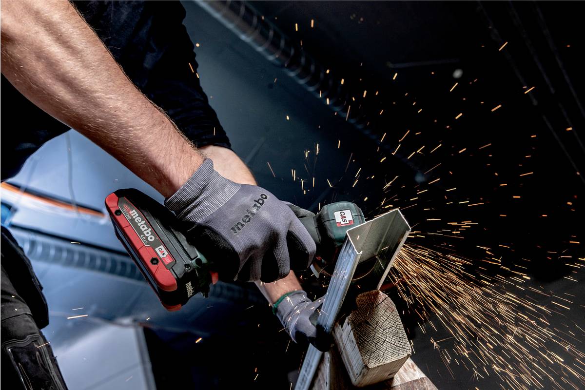 Een persoon snijdt metaal met een Metabo-haakse slijpmachine, vonken spatten. Veiligheidshandschoenen worden gedragen.