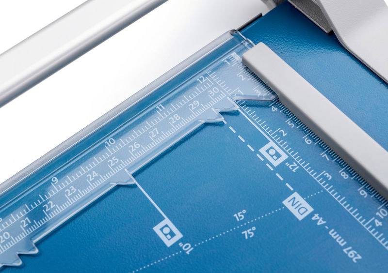 Papierschaar met liniaal en hoekmeetschaal op een blauw snijbord, toont DIN A4-markeringen en snijgeleidelijn.