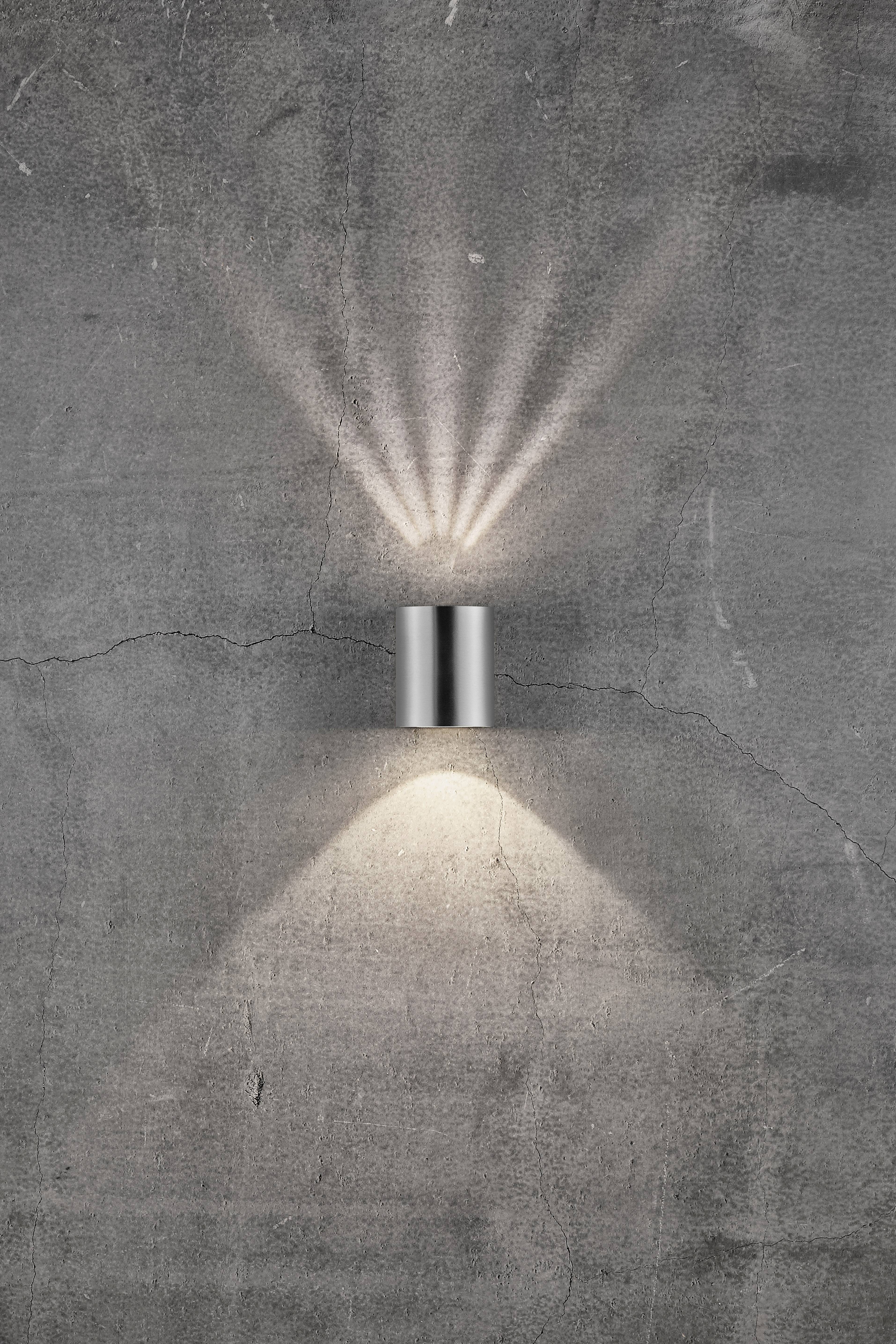 Wandlamp aan grijze betonmuur, straalt lichtstralen naar boven en geeft sterk licht naar beneden.