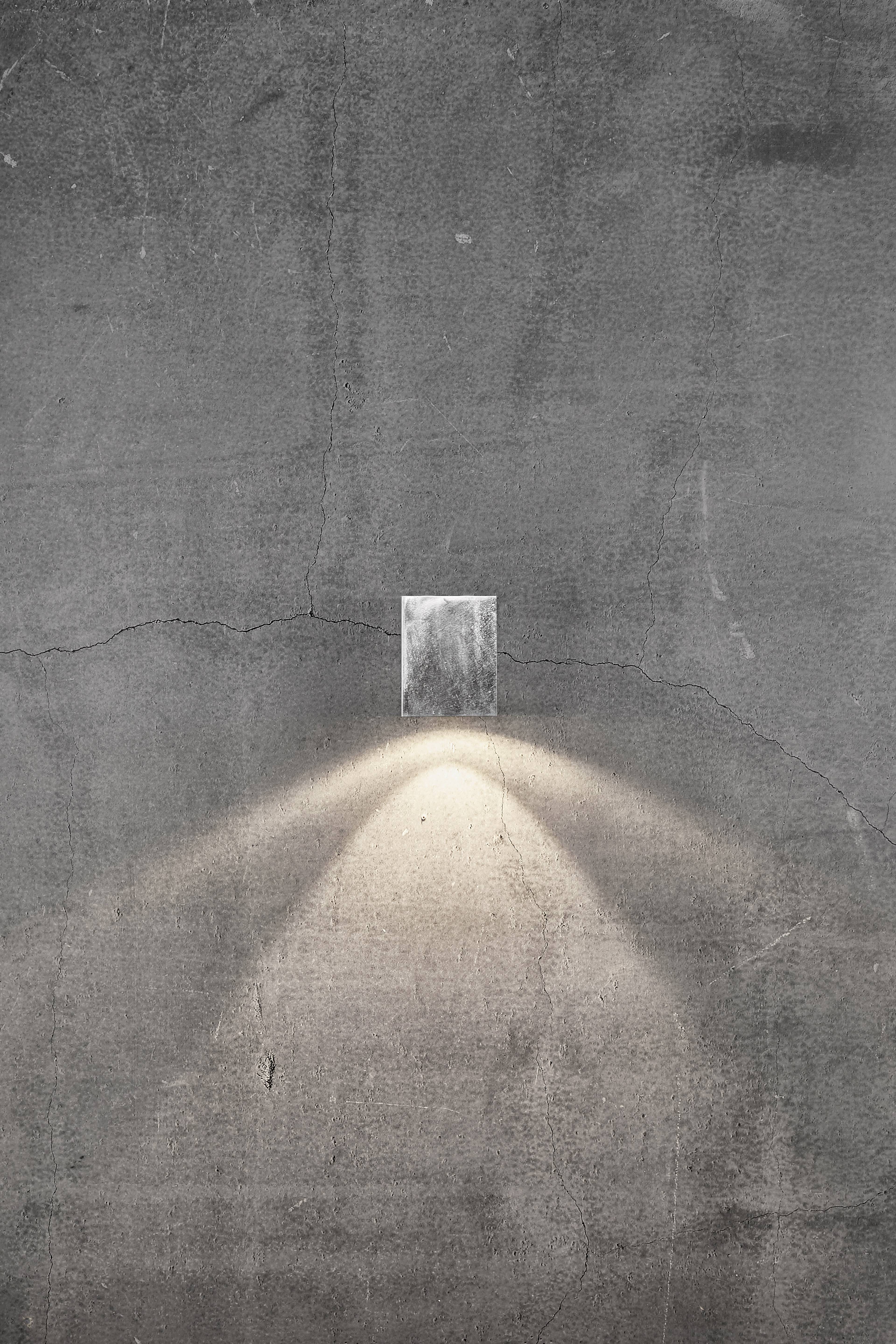 Een eenzame open deur in een betonnen muur, waar licht doorheen stroomt, symboliseert hoop of een nieuw begin.