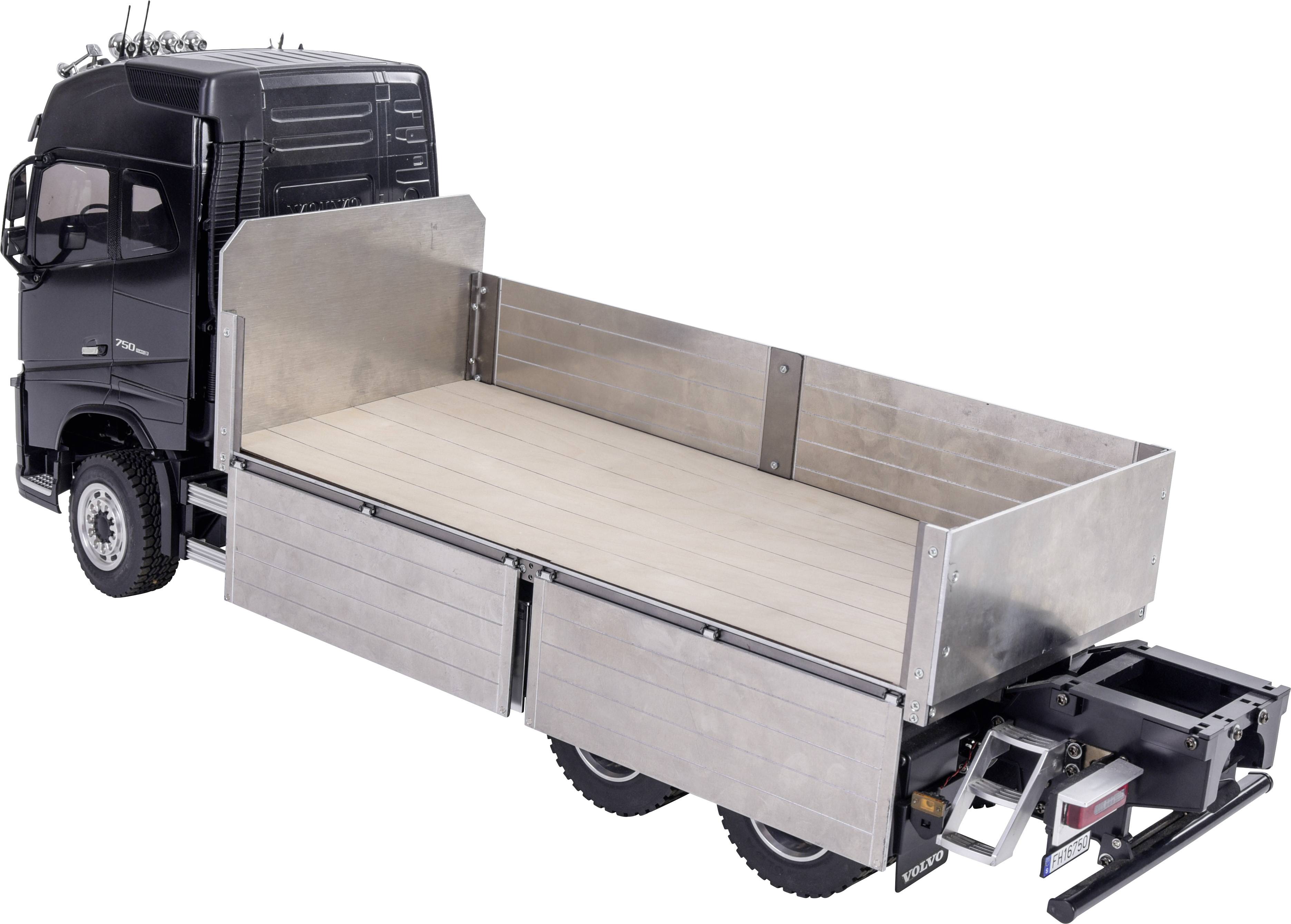 Een zwarte vrachtwagen met een open, metalen laadruimte zonder lading, waarbij enkele steunen zichtbaar zijn. Aanzicht van links achteren.