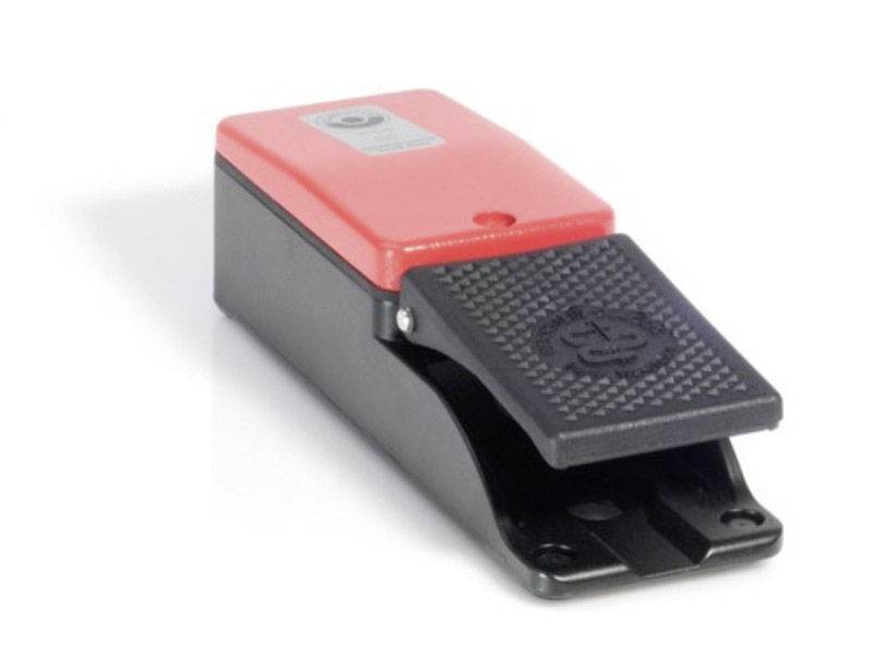 Een zwart en rood voetpedaal van kunststof, op een witte achtergrond.