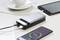 Een powerbank laadt twee apparaten op een tafel op: een smartphone met 71% batterij en een tablet. Op de achtergrond een kopje.
