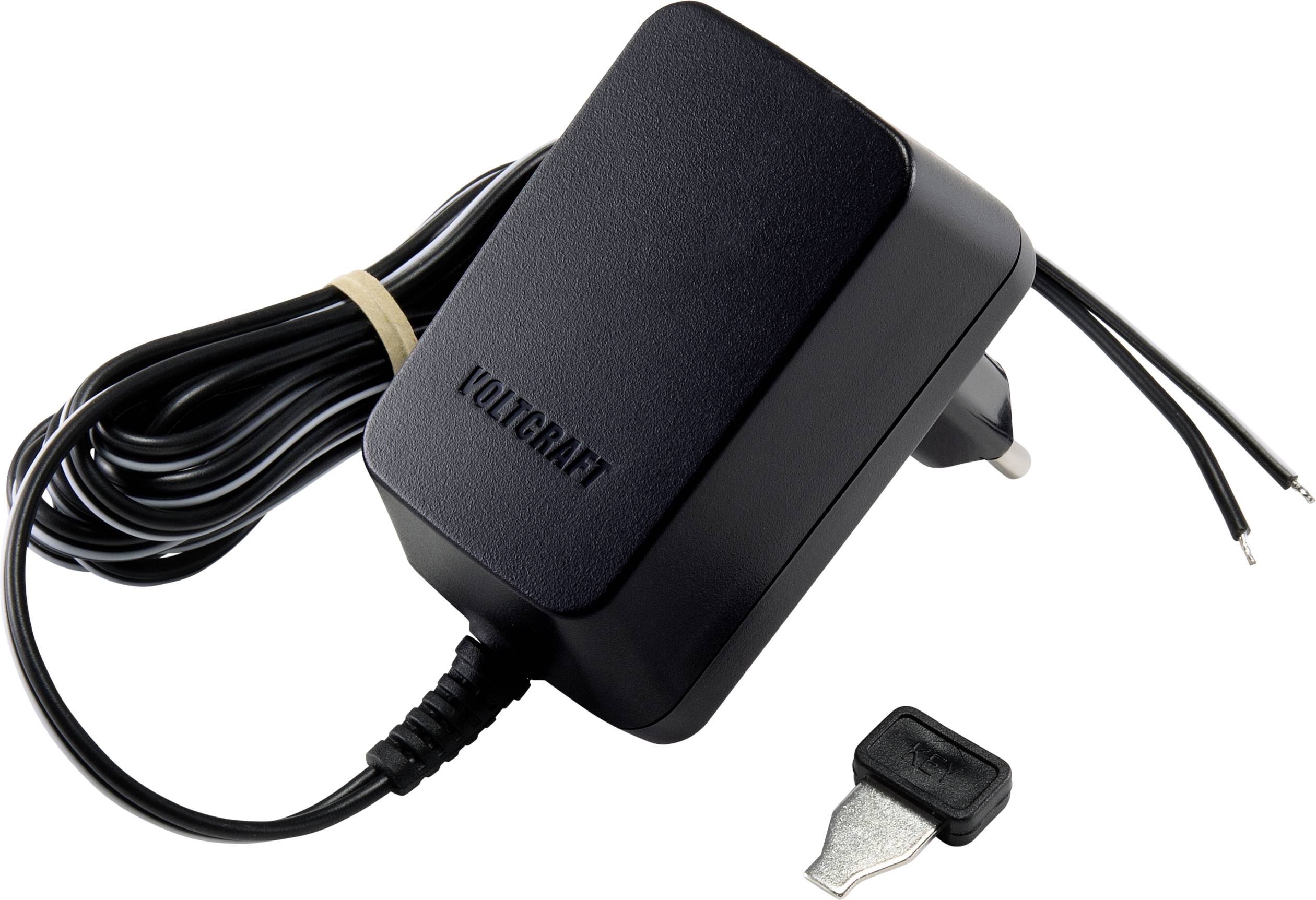 Een zwarte Voltcraft-voeding met open draadeinden ligt naast een metalen opzetstuk, vermoedelijk een adapter.