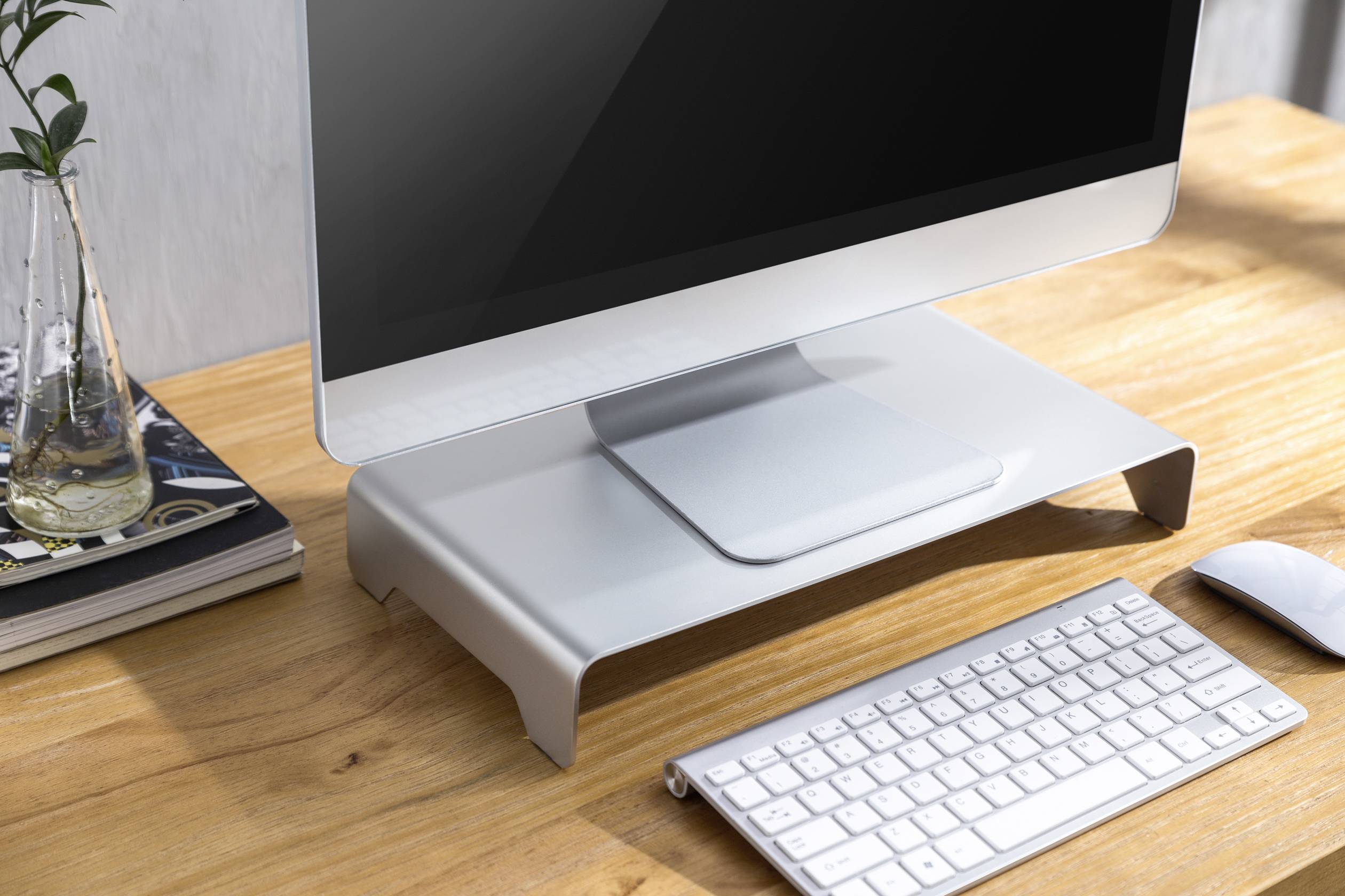 Een moderne computer op een houten bureau. Naast het scherm bevinden zich een toetsenbord, muis en planten.