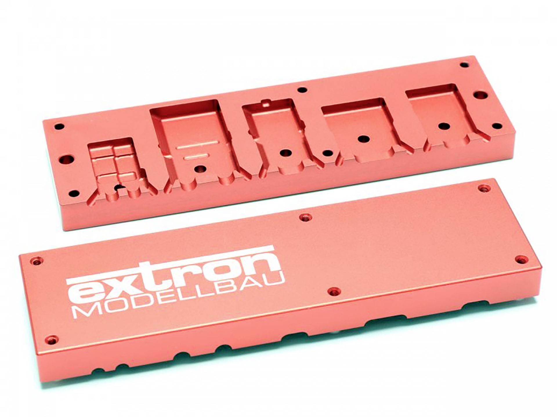 Twee rode metalen onderdelen, waarvan één met de opdruk 'extron MODELBOUW'.