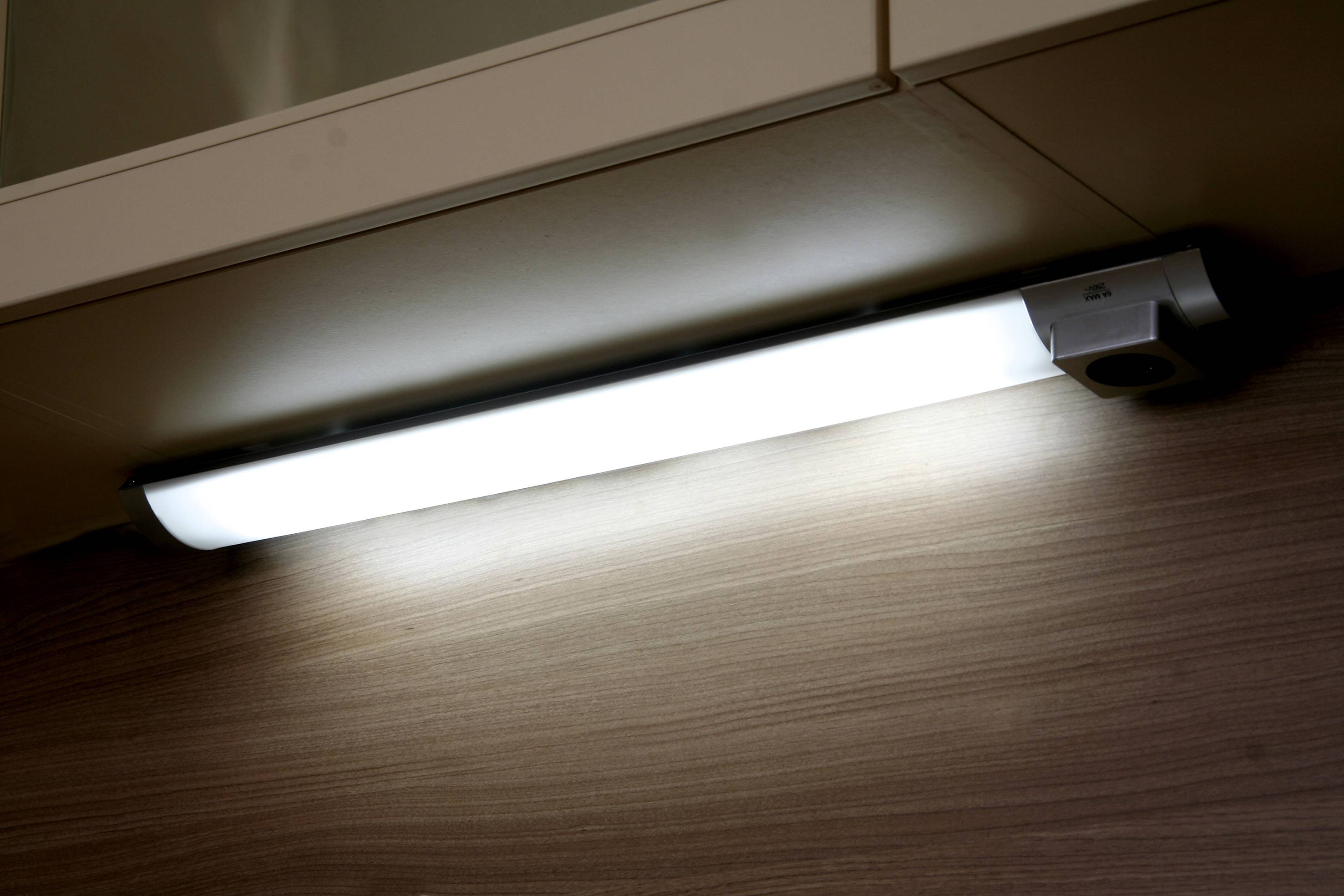 Tl onder een kast gemonteerde TL-buis die een oppervlak met houtnerf verlicht.