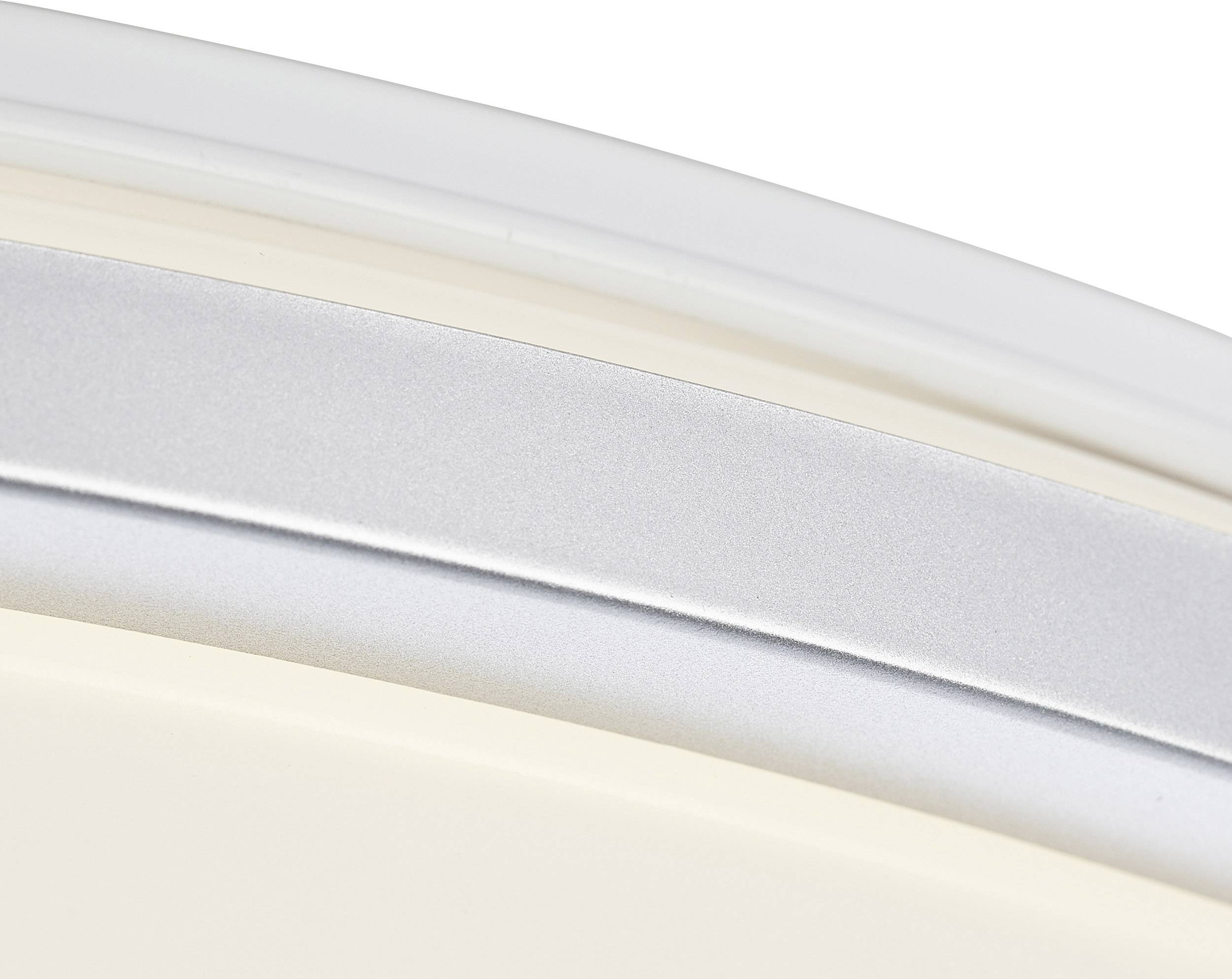 Een zilveren en witte gebogen metalen frame, mogelijk onderdeel van een modern meubelstuk of lamp, is zichtbaar.