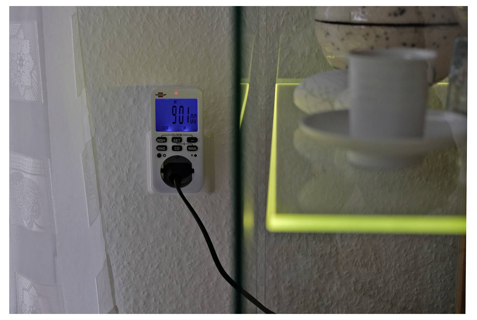 Een wandcontactdoos-timer met een blauw digitaal display ingesteld op 9:01 uur 's ochtends, met een ingeplugde stekker en een hangend snoer.