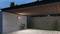 Moderne garage met houten plafond en verlichting, fiets leunend tegen betonnen muur, stenen muur op de achtergrond, omringd door bomen.