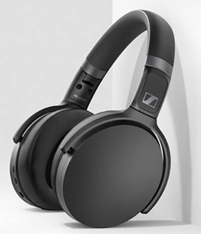 Zwarte draadloze koptelefoon met gepolsterde oorschelpen, leunend tegen een witte muur.