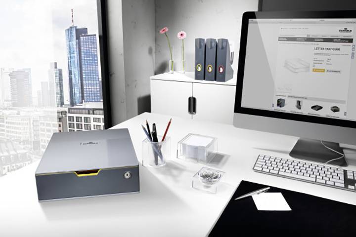 Een modern kantoor met uitzicht op een stad. Op de voorgrond staan een monitor met een geopende webwinkel, een toetsenbord en organisatiematerialen.