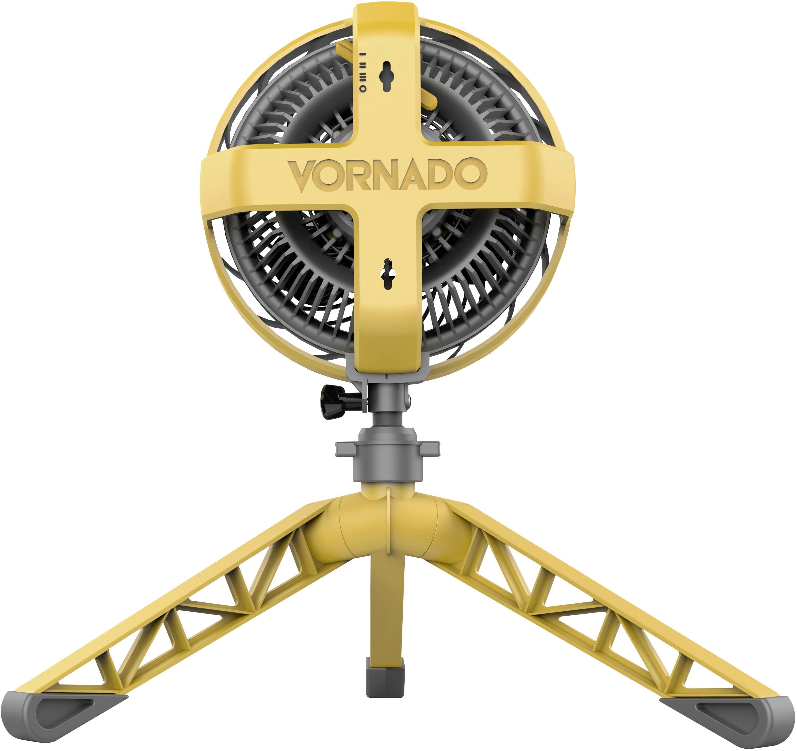 Gele statiefventilator met drie poten. De ventilatorkop is draaibaar en heeft het logo 'Vornado'. Hij is bedoeld voor gebruik binnenshuis.