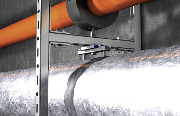 Een oranje buis loopt bovenaan een zilveren buis, bevestigd aan een metalen steun tegen een grijze muur.