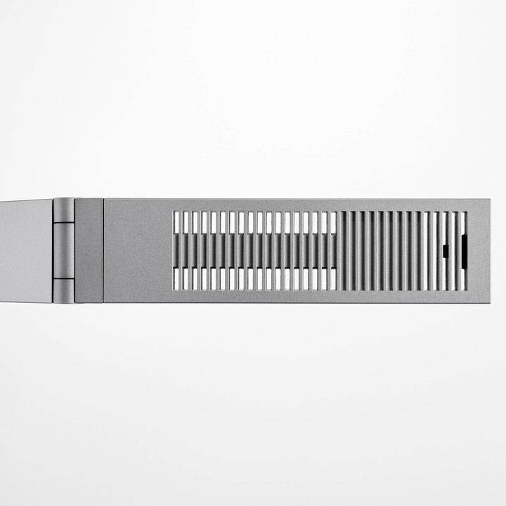 Een zilveren, rechthoekige radiator met verticale sleuven aan de voorkant. De radiator is aan de muur bevestigd.