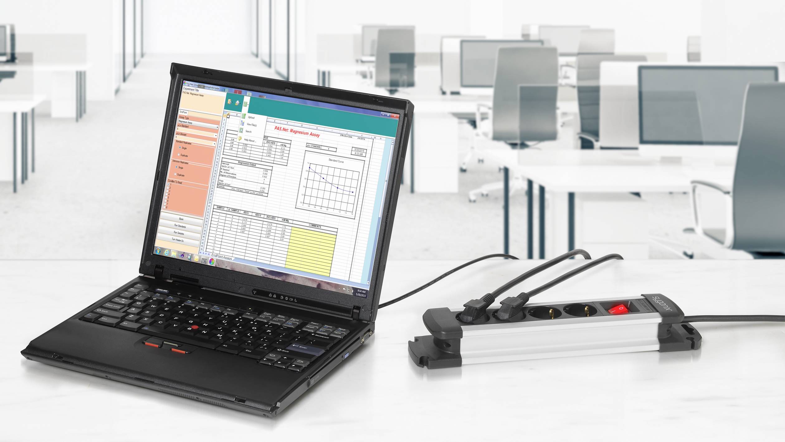 Een laptop toont een geopend diagramgereedschap op het scherm. Hij is aangesloten op een stroomverdeler. De achtergrond laat een leeg kantoor zien.