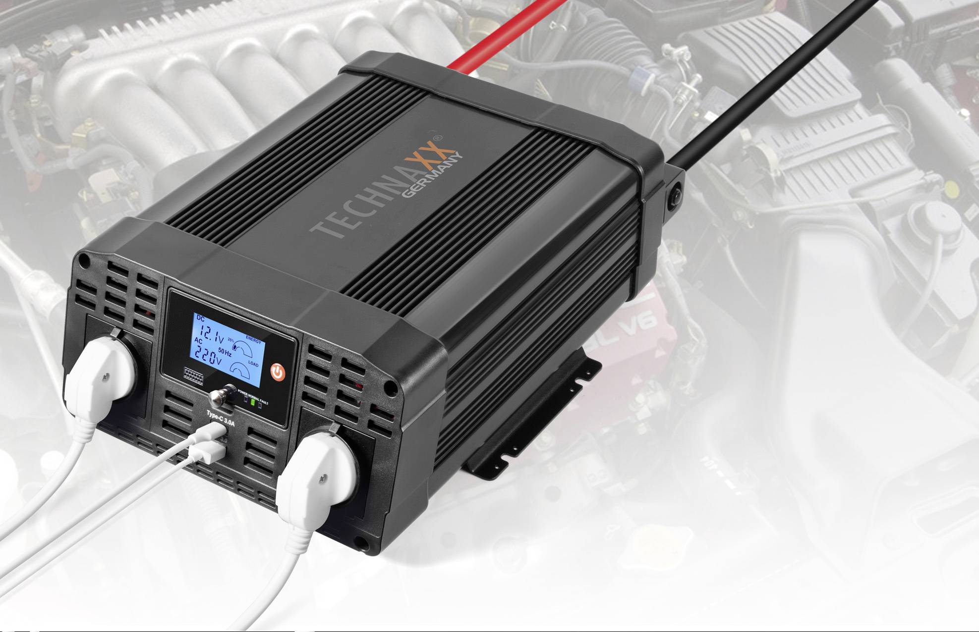 Een zwarte spanningsomvormer met display dat '12,2V 220V' weergeeft, is aangesloten op twee witte stekkers. Op de achtergrond een motor.