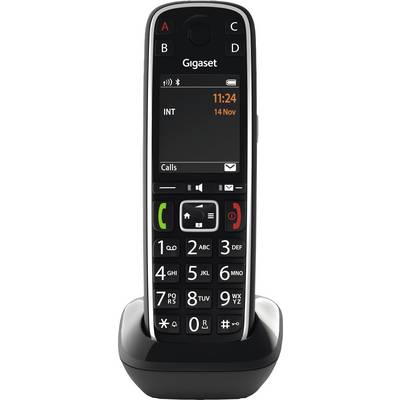 Draadloze telefoon in een laadstation. Groot zwart-wit toetsenbord met verlicht display dat tijd en datum weergeeft.