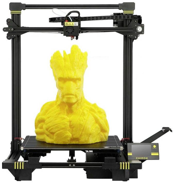 Een 3D-printer drukt een grote, gele standbeeld van een boomachtig wezen met armen en een gezichtsuitdrukking.