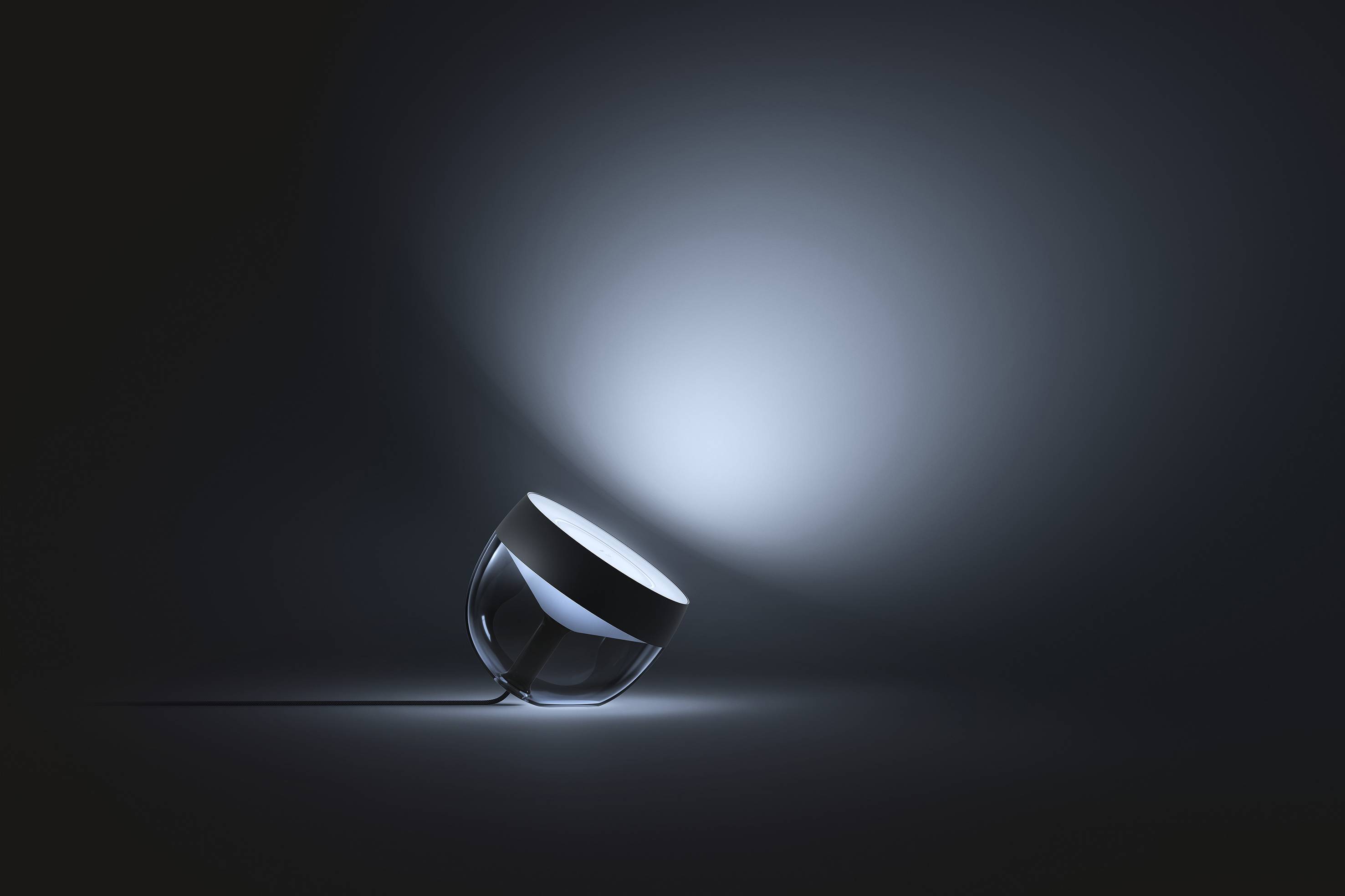 Een moderne glazen bol-lamp die schuin ligt en zacht licht uitstraalt in een donkere ruimte. De verlichting creëert een rustgevende sfeer.
