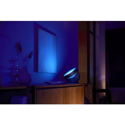 Een slimme projector werpt blauw licht op een witte muur en verlicht daarmee een modern woonvertrek met meubels en decoraties.