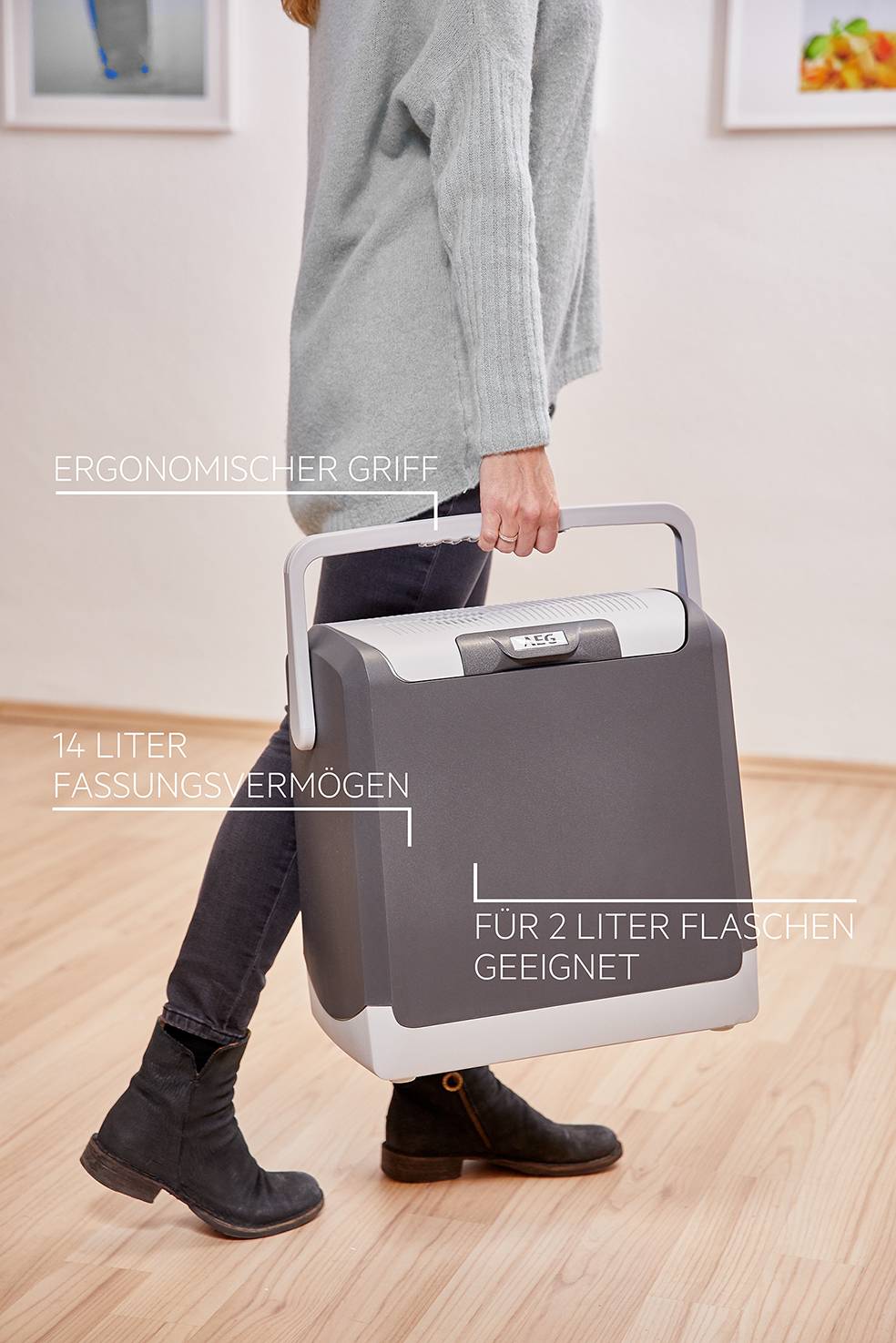 Persoon draagt een draagbare koelbox met ergonomische handgreep, met een inhoud van 14 liter, geschikt voor 2-literflessen.