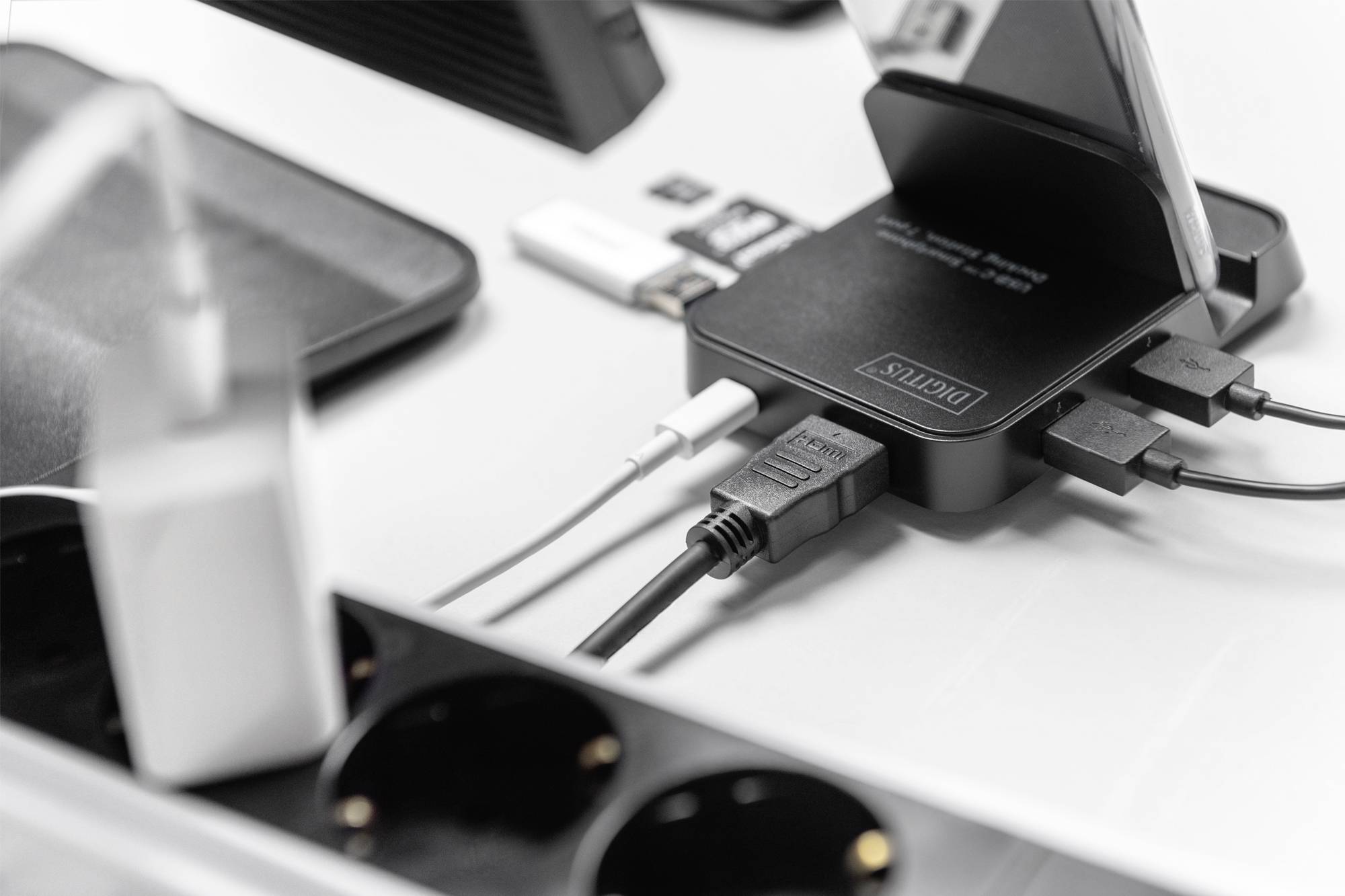 Meerdere apparaten zijn aangesloten op een laadstation. Er zijn verschillende kabels, USB-stekkers en een rechtop staande smartphone te zien.