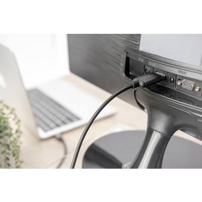 Een computerscherm is via een HDMI-kabel verbonden met een laptop. Op de voorgrond is een deel van het bureau zichtbaar.