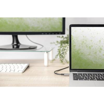 Een laptop en een monitor op een bureau, waarbij beide schermen een groen spatpatroon tonen. Op de achtergrond een plant.