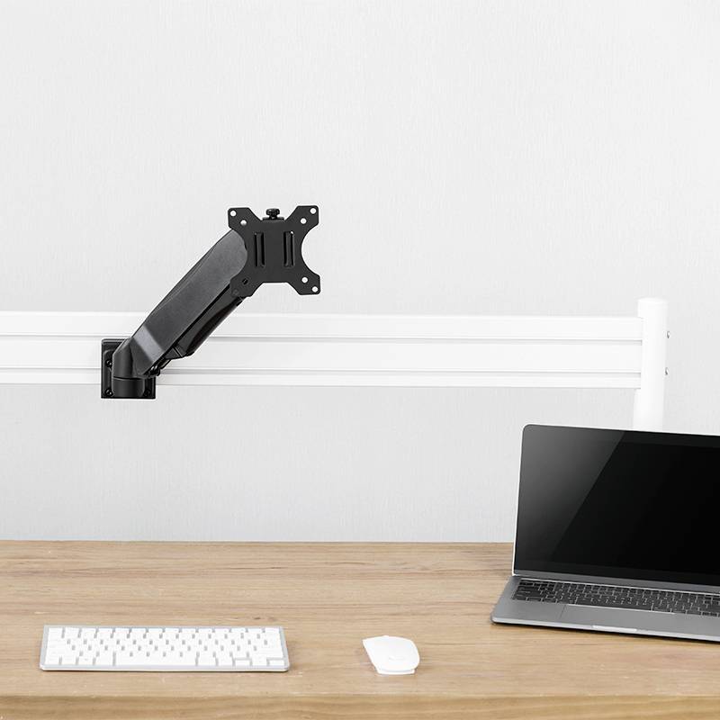 Een leeg bureaulandschap met een laptop, een muis en een toetsenbord. Een monitorarm zonder monitor is ook zichtbaar.