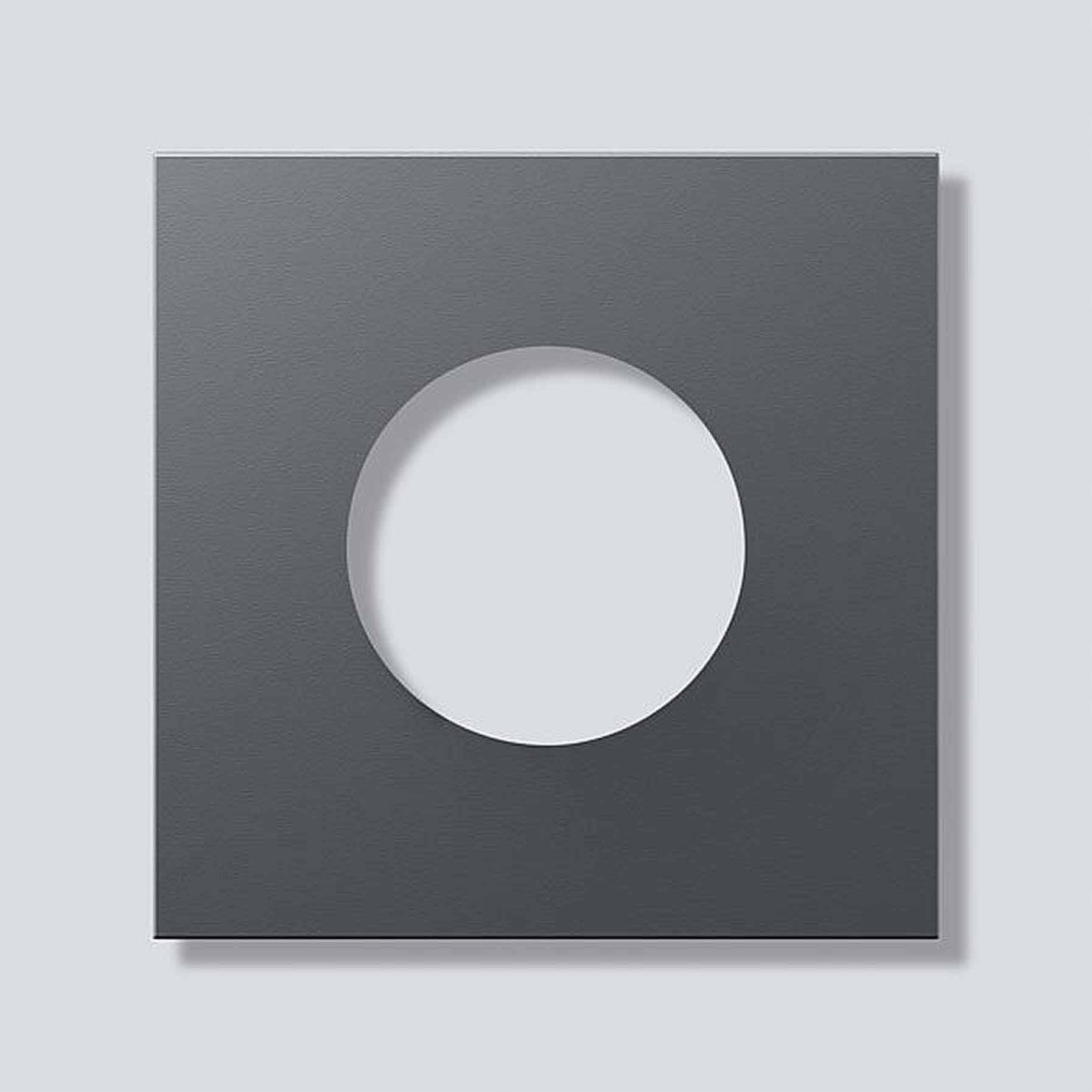 Donker vierkant met een rond gat in het midden, op een lichtgrijze achtergrond. Minimalistische kunst.
