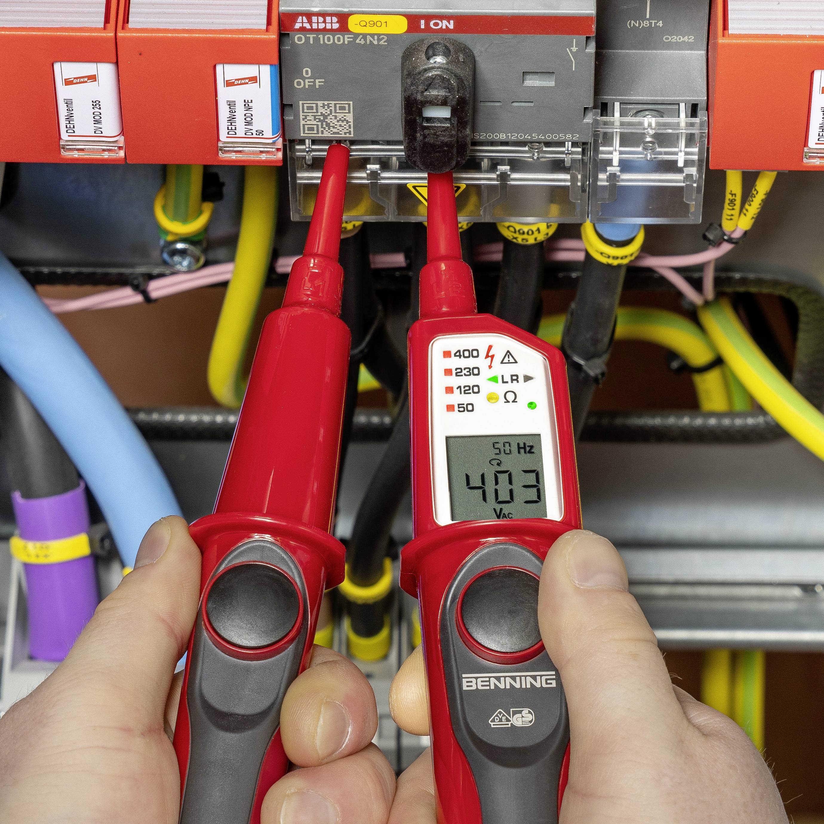 'Close-up van een elektricien die met een multimeter de spanning meet aan elektrische componenten in een schakelkast.'