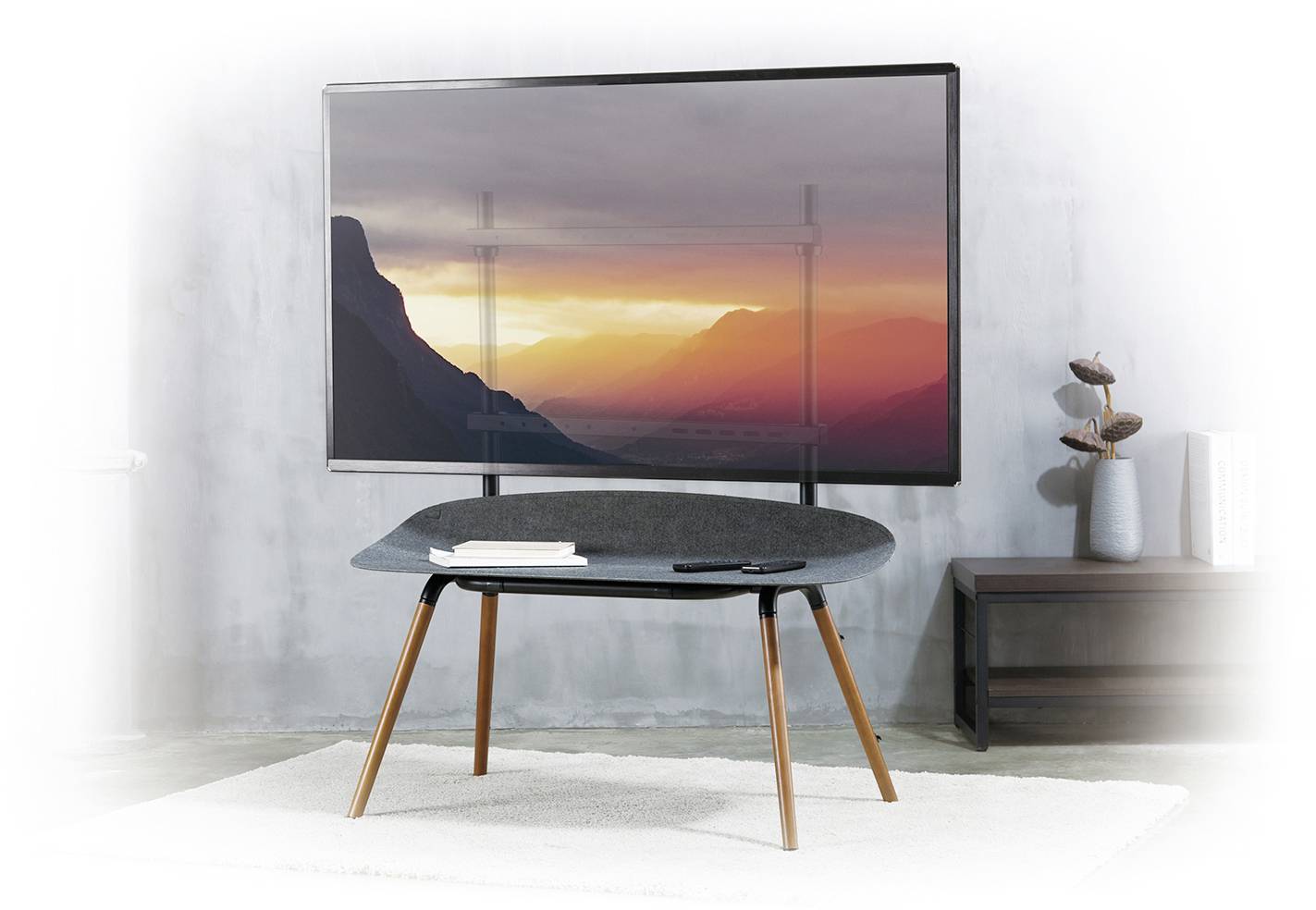 Een woonkamer met een moderne televisie die een berglandschap bij zonsondergang laat zien, met daarvoor een stijlvolle, zwarte tafel.
