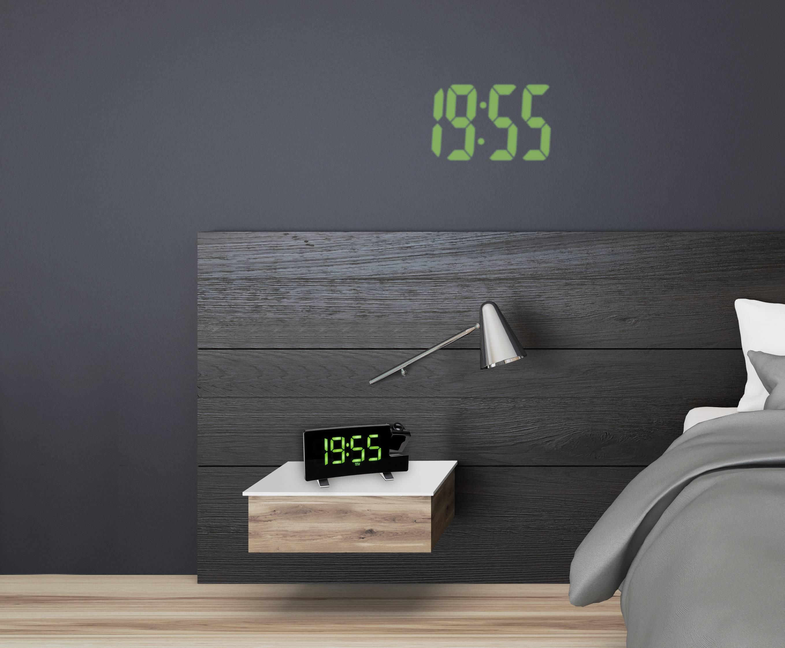 Een moderne slaapkamer met een digitale klok aan de muur die '18:55' aangeeft. Ernaast een tafellamp en een bed met grijze beddengoed.