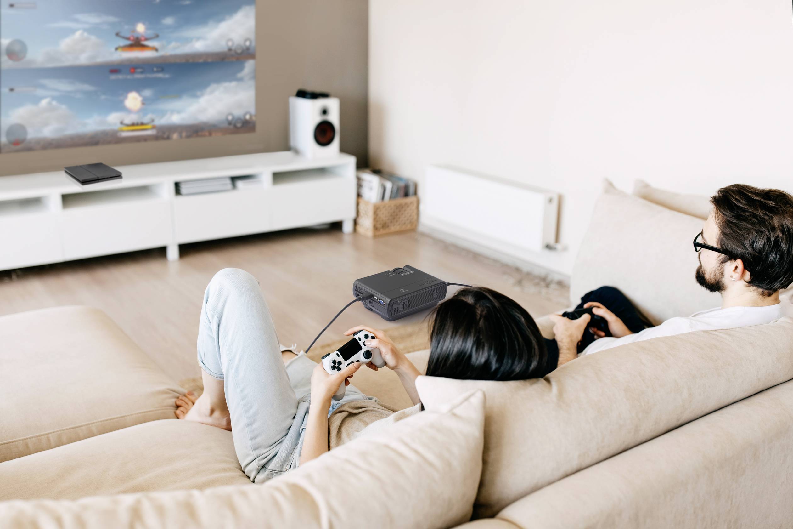 Een stel zit op een bank in een woonkamer en speelt videogames op een grote tv. Beiden houden een controller in hun hand.