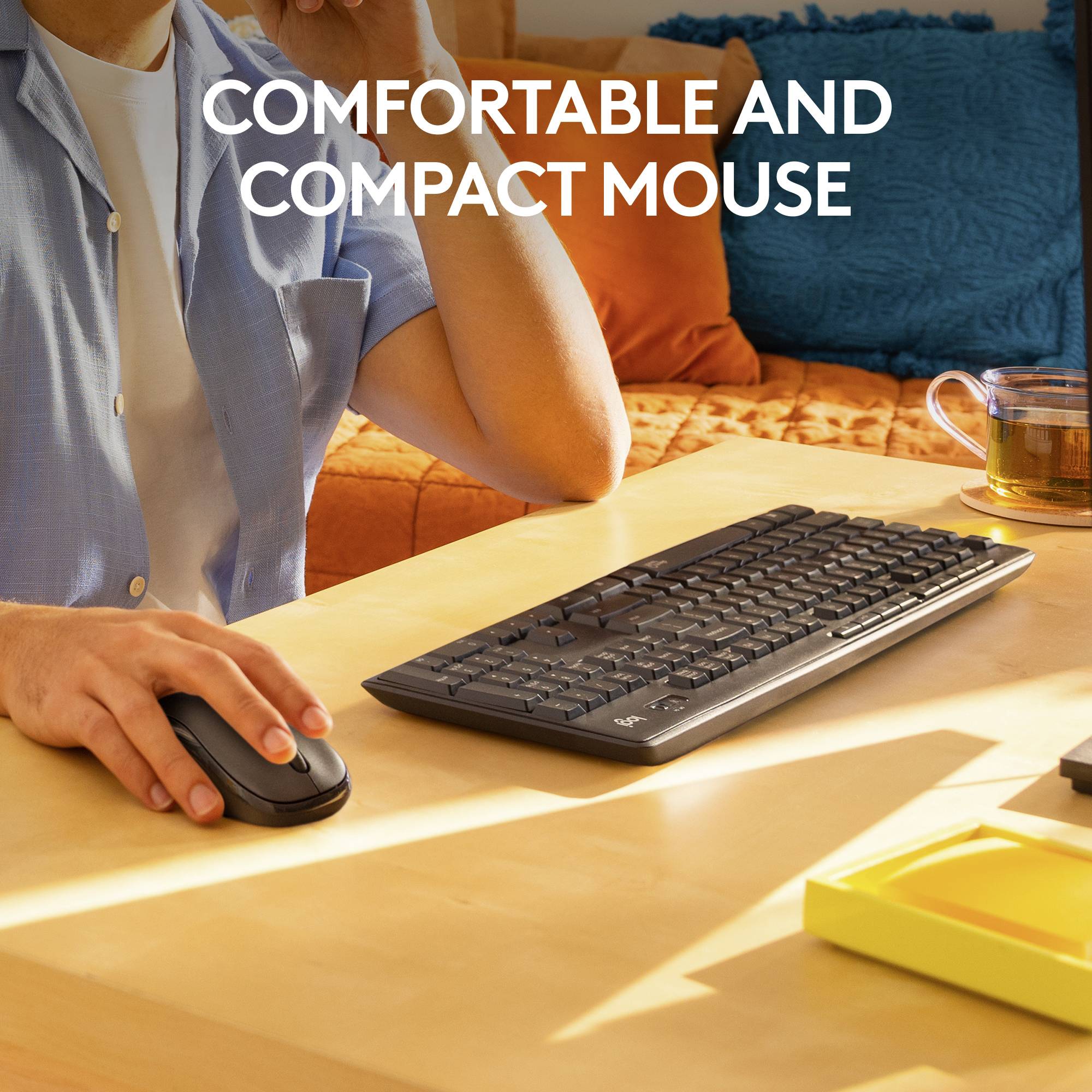 Een persoon aan een bureau houdt een ergonomische muis vast; naast haar bevinden zich een toetsenbord en een kopje. Tekst: 'Comfortabele, compacte muis'.