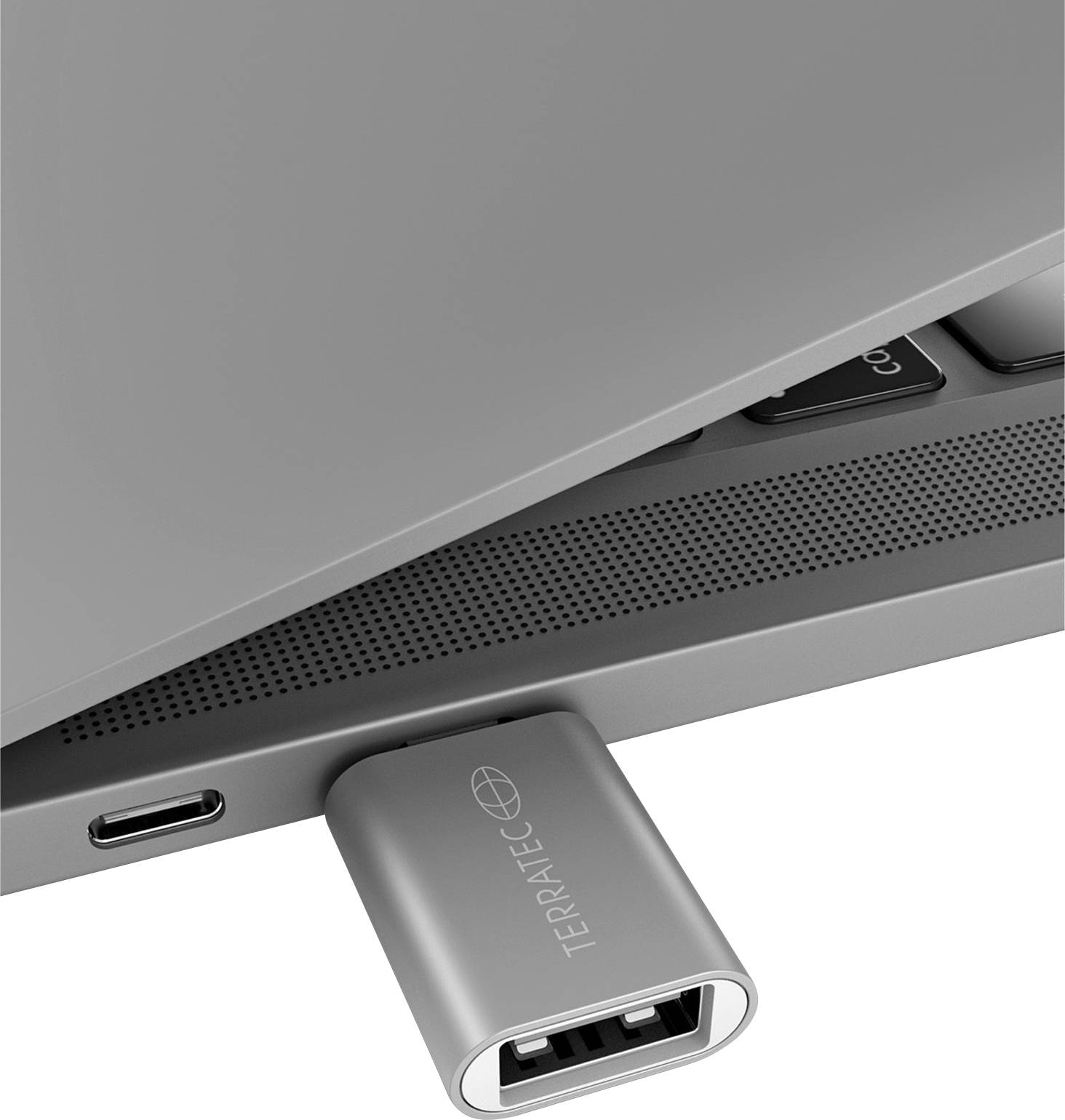 Een zilveren USB-adapter is zijdelings in een laptop gestoken, in de buurt van nog een USB-C-aansluiting.