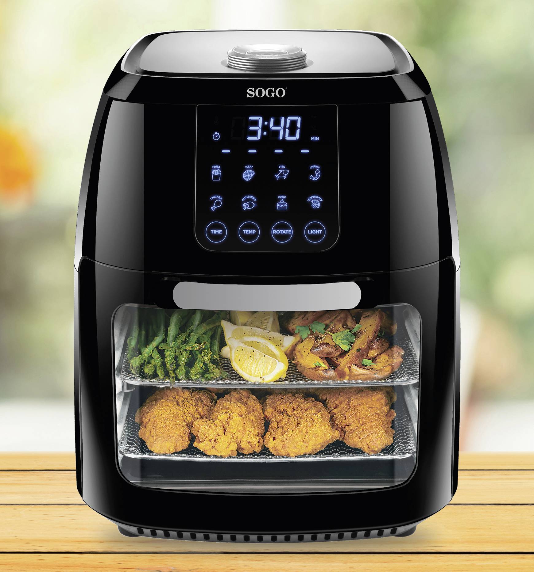 Heteluchtfriteuse met digitaal display toont '3:40'. Binnenin bevinden zich plateaus met gefrituurde kip, asperges en citroenschijfjes.